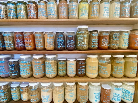 Horizontal shelves of glass jars with health and healing micronutrient medicinal powders, herbs & spices in whole foods store Byron Bay NSW Australia