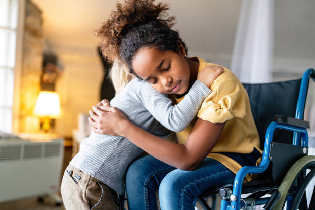 black little girl with disability in wheelchair hugging with her younger brother. - african ethnicity brother ethnic little boys imagens e fotografias de stock