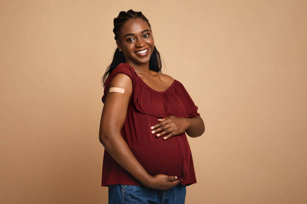 fröhliche schwangere schwarze frau wurde gegen covid-19 geimpft - photography color image colors studio shot stock-fotos und bilder
