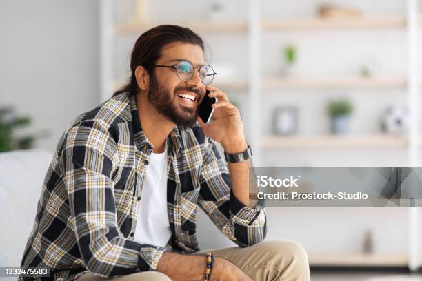 Cheerful Guy Relaxing On Couch At Home Having Phone Talk Stock Photo - Download Image Now