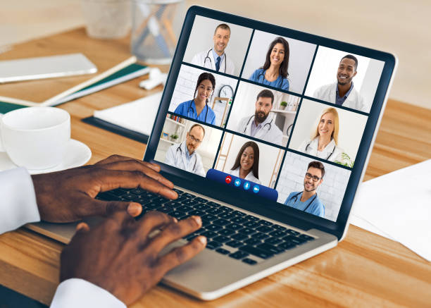 medico nero al laptop con videoconferenza con i colleghi al coperto - teleconferenza foto e immagini stock