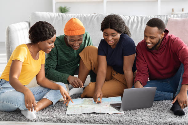 istock Smiling black friends planning vacation, using map and laptop 1332476081