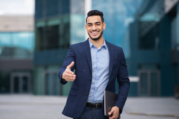 istock Positive arab man in formal suit outstretching hand towards camera 1332476452