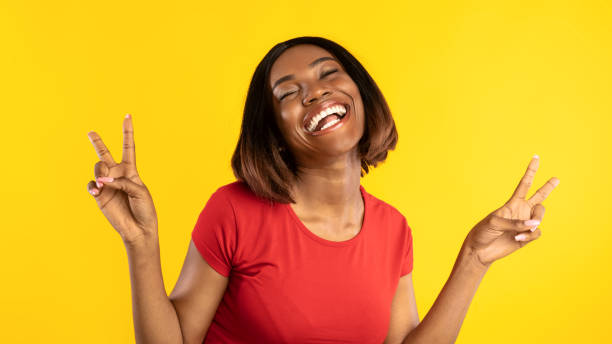 istock Happy Black Lady Gesturing Victory With Both Hands, Yellow Background 1332476611