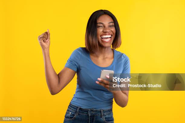 Happy Black Lady Holding Phone Gesturing Yes Over Yellow Background Stock Photo - Download Image Now