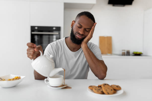 istock Black man pouring coffee away from cup spilling hot drink 1332478152