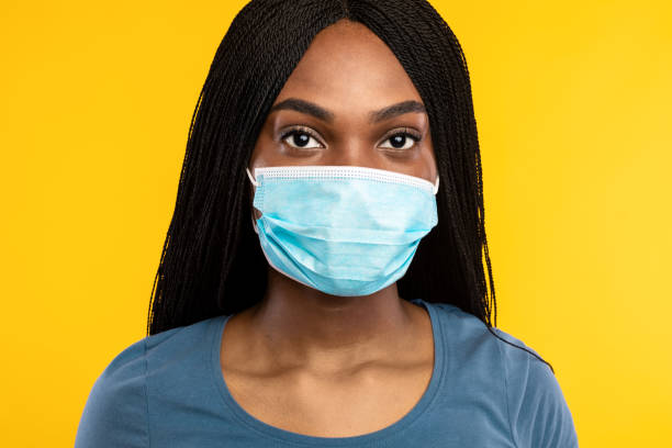 istock Black Millennial Lady Wearing Face Mask Over Yellow Studio Background 1332478199