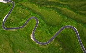 Passo di Giau Green hills Aerial drone shot of curved mountainous snake road. Traveling, transportation, safety driving, traveling, car rental concept.