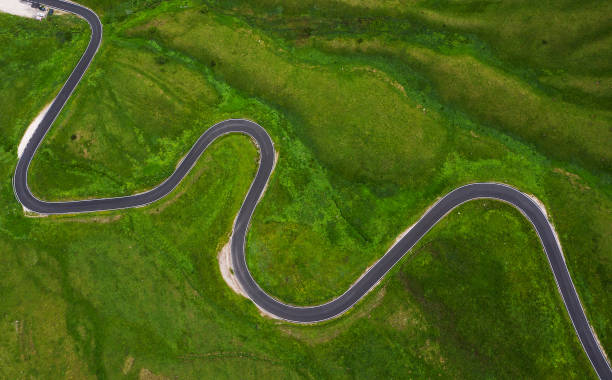 passo di giau green hills aerial drone shot of curved mountainous snake road. traveling, transportation, safety driving, traveling, car rental concept. - road top view imagens e fotografias de stock