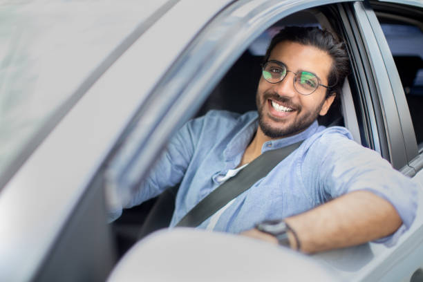 istock Handsome middle-eastern man driving car, shot from outside 1332478484