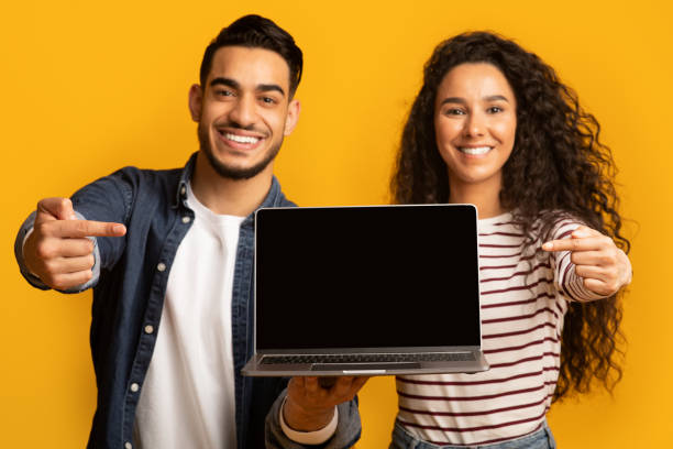 Great Website. Smiling middle eastern couple pointing at laptop with black screen