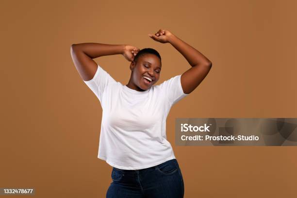 Portrait Of Casual Young Black Woman Dancing Brown Wall Stock Photo - Download Image Now