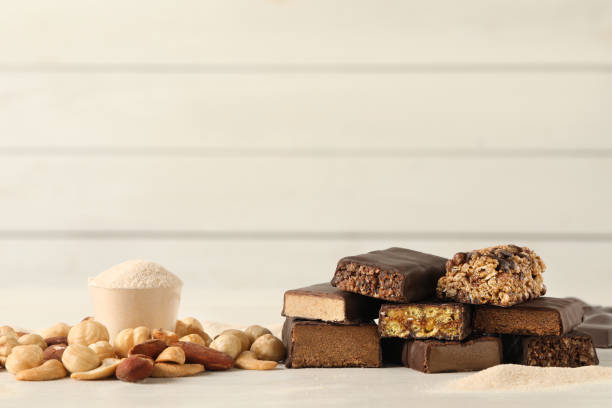 istock Different tasty energy bars, nuts and protein powder on white table, space for text 1332480976