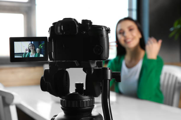 istock Young blogger recording video at cafe, focus on camera screen 1332482200