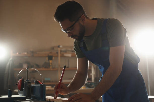 istock Professional carpenter making mark on wooden board in workshop 1332482419