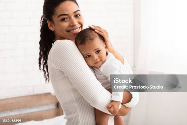 African American Mother Holding Her Baby Son Standing In Bedroom Stock Photo - Download Image Now