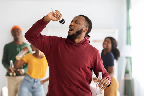 istock Positive black guy with bottle of beer singing karaoke 1332485637