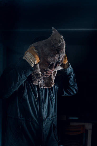 istock Murderer putting on a mask in the dark spooky room. 1332486850