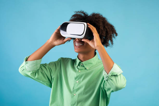 Experiencing futuristic technologies. Black guy wearing and touching VR headset, exploring cyberspace, blue background