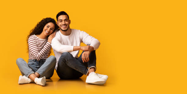 istock Happy Young Middle Eastern Spouses Sitting On Floor Over Yellow Background 1332488047