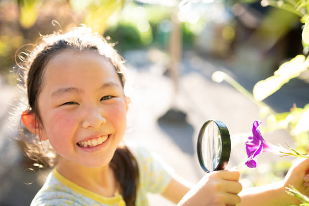 istock Girl observes morning glory with magnifying glass 1332488262