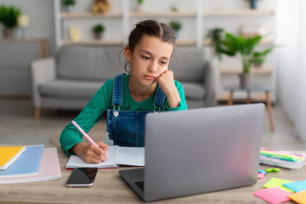 istock Tired school girl writing in notebook doing homework 1332489677