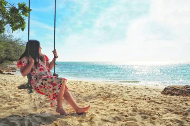 istock woman sitting in a hammock on the beach 1332492348