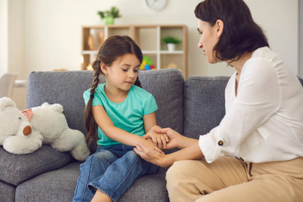 Mother sitting with daughter, holding her hands, talking to her and teaching her something stock photo