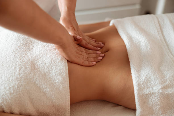 istock Masseuse massaging female client abdomen in spa salon 1332500906