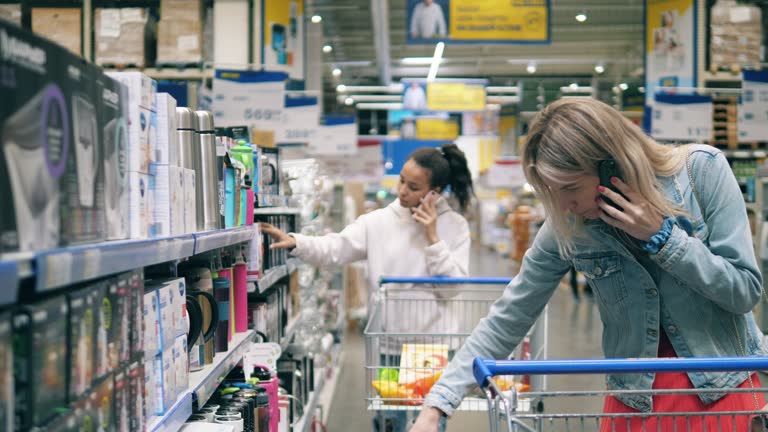 Supermarket with ladies choosing stuff and talking over the phone. Woman at a supermarket, consumerism concept.