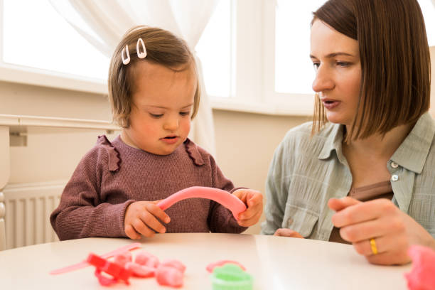 istock Girl with down syndrome holding plasticine while sculpting with her mother 1332503010