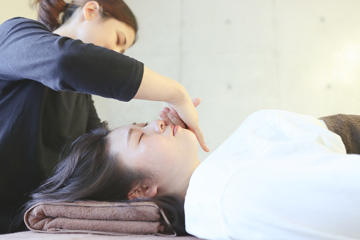 Asian woman take a beauty facial massage at aesthetic salon.  A massage to make a face smaller and face lifting.