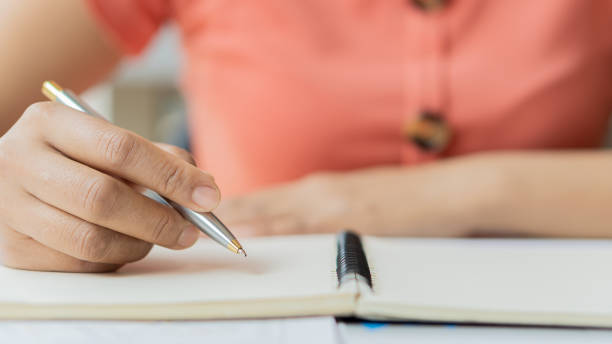 istock girl's hand holding a pen to write in a notebook making financial transactions 1332505883
