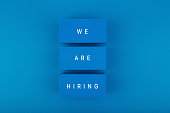 Job opening concept. We are hiring written on blue toy blocks against blue background