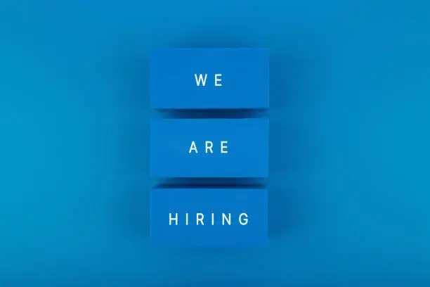 Photo of Job opening concept. We are hiring written on blue toy blocks against blue background