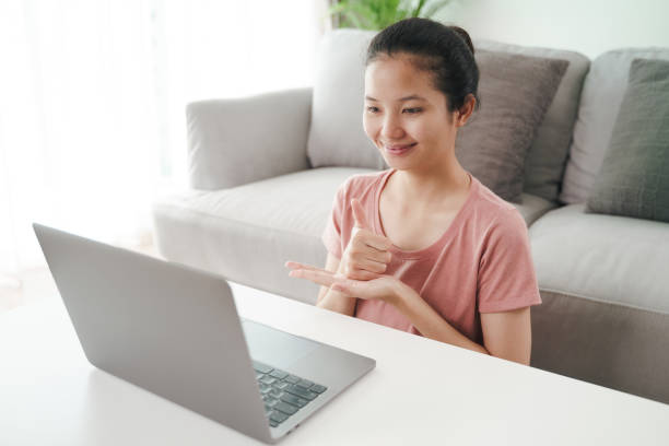 istock Young Asian woman deaf disabled using laptop computer for online video conference call learning and communicating in sign language. 1332509724
