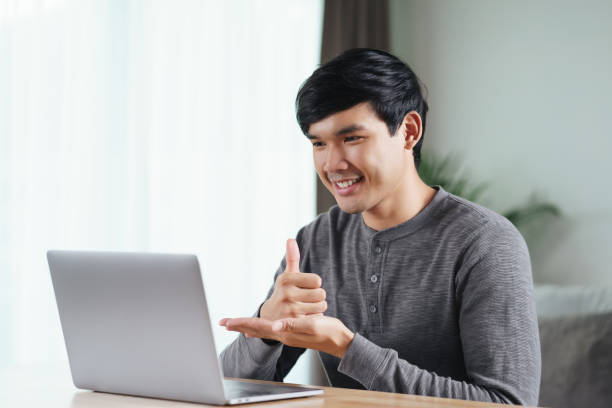 Young Asian man deaf disabled using laptop computer for online video conference call learning and communicating in sign language. Young Asian man deaf disabled using laptop computer for online video conference call learning and communicating in sign language. deaf stock pictures, royalty-free photos & images