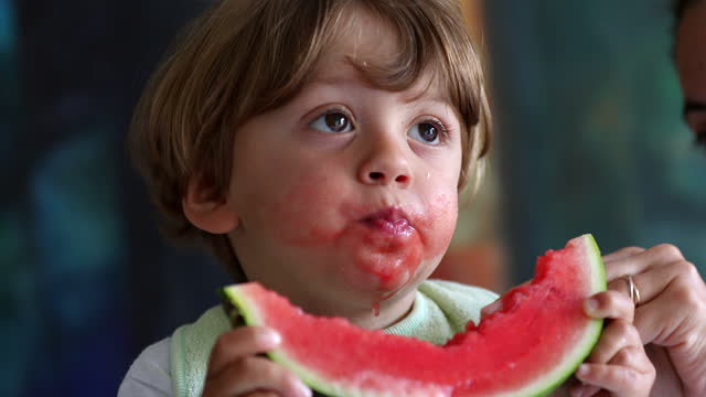 Kid eating red watermelon fruit,  messy child eats healthy food