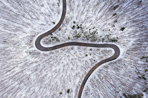 curvy country road in winter forest from drone point of view