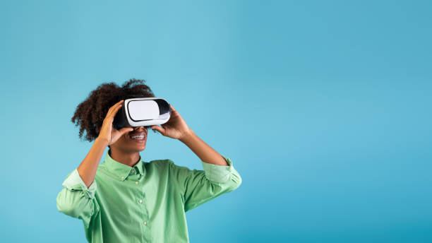 istock Modern gaming. African american guy wearing VR headset, exploring cyberspace, blue background, panorama with empty space 1332518013