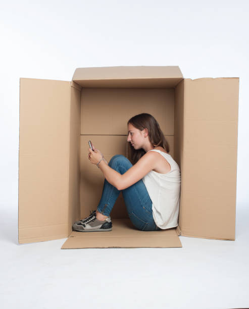 mujer joven usando teléfono inteligente dentro de una caja - pessimist women one person caucasian fotografías e imágenes de stock