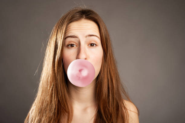 istock young woman making a bubble from a chewing gum 1332518900