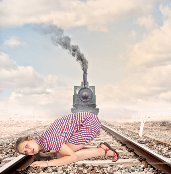 young woman with ear on train track listening to the arrival of an steam locomotive