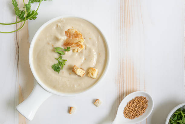 cauliflower cream soup, croutons and herbs in white bowl with copy space - cauliflower vegetable portion cabbage imagens e fotografias de stock