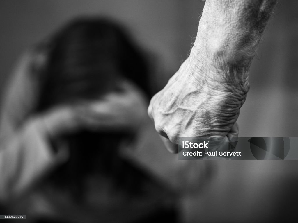 Domestic violence mans clenched fist Domestic violence man against woman clenched fist black and white image Violence Stock Photo