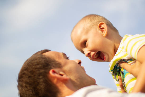 szczęśliwy ojciec wyrzuca swojego małego syneczka na tle nieba. - facial expression babies and children head and shoulders close up zdjęcia i obrazy z banku zdjęć