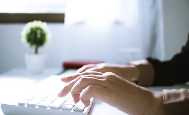 istock Woman working by using a laptop computer on wooden table. Hands typing on a keyboard 1332524652