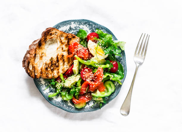 istock Delicious breakfast, snack - salad with salmon, egg, vegetables, lettuce and grilled bread on a light background, top view 1332525992