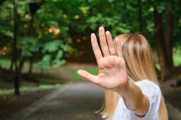 Girl covers her face with hand stop gesture. Negative defensive concept of communication psychology. Woman rejects offer and shows hold sign stock photo