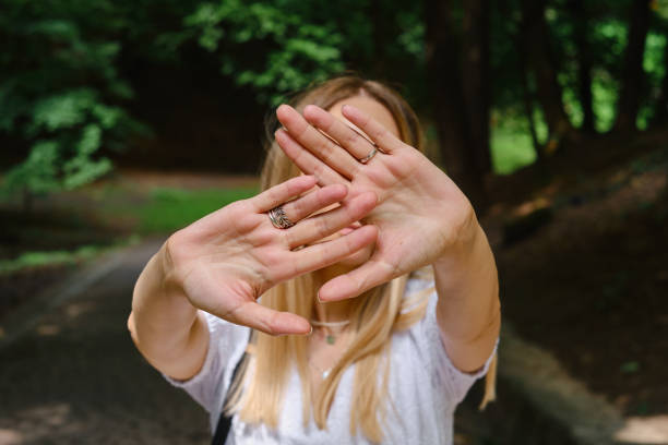 istock Girl covers her face with hand stop gesture. Negative defensive concept of communication psychology. Woman rejects offer and shows hold sign 1332530721